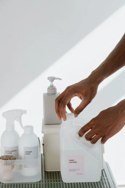 Person using spray bottle and cloth for cleaning a kitchen shelf, ensuring hygiene and cleanliness.